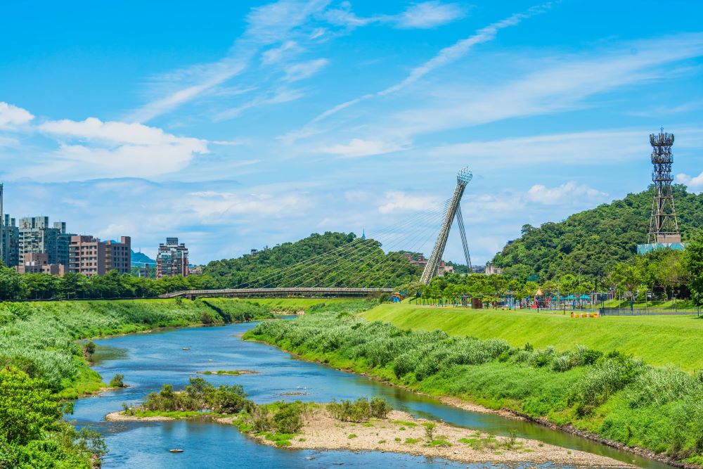 《圖說》汐止的地標「星光橋」兩側擁有風景秀麗的河濱自行車道以及綠意盎然的草坡綠野。〈水利局提供〉