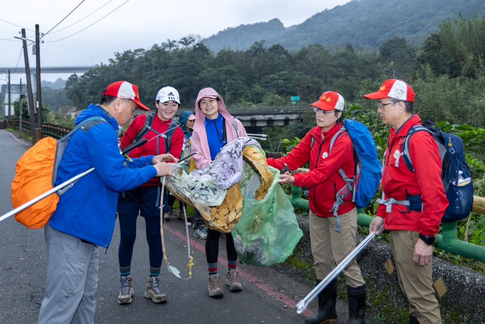 《圖說》參與民眾手持長夾與垃圾袋，沿步道拾起天燈殘骸及垃圾。〈觀旅局提供〉