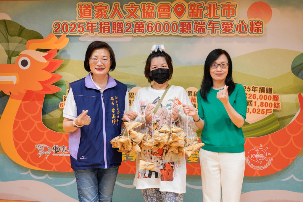 道家人文協會理事長張旖右1代表捐贈愛心粽，與新北社會局長李美珍左1一同將粽子給予受贈代表小錡中